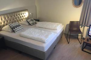 a bedroom with two beds and a chair and a television at Aquaronde 122 in Lemmer