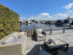 a patio with wicker furniture and a view of a river at Aquaronde 117 in Lemmer