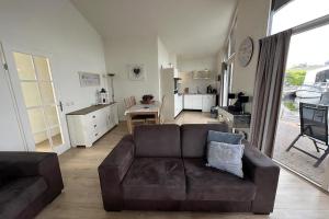 a living room with a brown couch and a kitchen at Aquaronde 120 in Lemmer