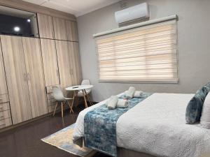 a bedroom with a bed and a window and a table at Palm Guesthouse in Zeerust