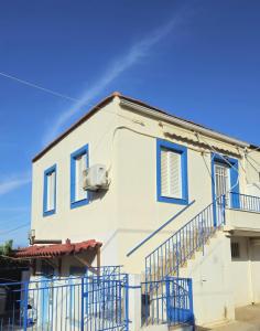 a white house with blue windows and a balcony at Mary's apartment Elaia 3 in Elia Laconias