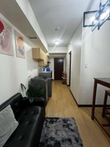 a living room with a black leather couch in a room at Celeste Stays- Celandine in Sampong +3 photos