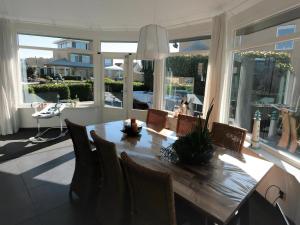 a dining room with a table and chairs and windows at Park De Markol Leeuwerik 12 in Lemmer