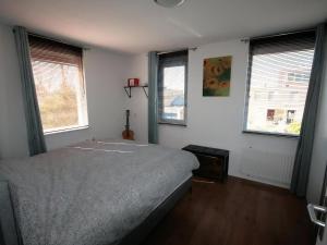 a bedroom with a bed and two windows at Park De Markol Leeuwerik 12 in Lemmer