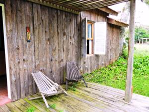 two chairs sitting on a deck next to a building at Aldeia Santuario das Aves in Tavares