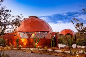 a domed building with two domes and white chairs at Cipó Cabanas in Santana do Riacho