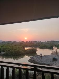 a man standing on the shore of a river at sunset at Thiptavanh guesthouse in Don Det +11 photos