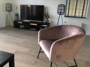 a living room with a pink chair and a television at Park De Marol Grutto 8 in Lemmer