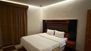 a bedroom with a white bed with a black headboard at شقق عناوين الفخامة in Şāmitah +2 photos
