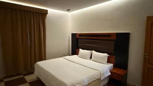 a bedroom with a white bed with a black headboard at شقق عناوين الفخامة in Şāmitah