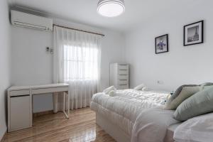 a white bedroom with a bed and a desk at Winahost Villa Unión in Puebla de Vallbona +18 photos
