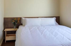 a bed with white sheets and a vase of flowers on a table at Camping Taiga Lake Caspe - Maeva Vacansoleil in Caspe +20 photos