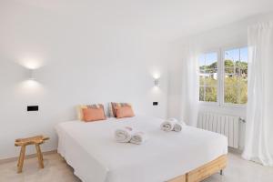 a white bedroom with a large bed with towels on it at Villa Sa Sirvi in Santa Ponsa