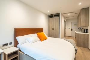 a bedroom with a white bed with an orange pillow at For Students Only Space St Andrews in St. Andrews +6 photos