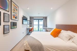 a bedroom with a white bed with an orange pillow at For Students Only Space St Andrews in St. Andrews
