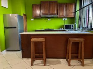 a kitchen with wooden cabinets and green walls at TheGatsbyStyle by EcoPact in Dar es Salaam