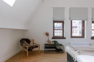 a bedroom with a bed and a chair and windows at Bright Duplex near Antwerp Cathedral in Antwerp