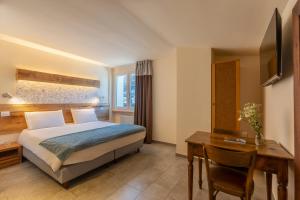 a hotel room with a bed and a desk at Hirondelle Locanda Vegana in Aosta