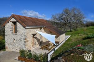 a small stone house with a picnic table in a yard at L'écrin de lacoste in Chasteaux