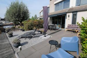 a patio with chairs and tables and a purple umbrella at Park Brekkense Wiel 103 in Lemmer