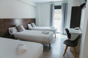 a hotel room with two beds and a chair at Imprenta Musical Alojamiento in Astorga