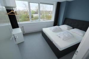 a bedroom with a bed with white pillows and a window at Park Brekkense Wiel 103 in Lemmer