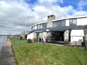 a house with a lawn in front of a body of water at Park Brekkense Wiel 037 in Lemmer