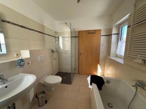 a bathroom with a toilet and a tub and a sink at Ferienhaus Weimarer Land in Berlstedt +6 photos