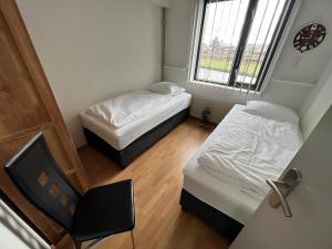 a small room with two beds and a chair at Park Brekkense Wiel 037 in Lemmer