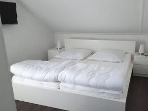 a white bed with white sheets and pillows on it at Park De Markol River House in Lemmer