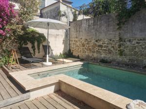 a swimming pool in a backyard with an umbrella at Résidence des Abeilles in Avignon