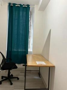 a desk and a chair in a room with a green curtain at City centre appartement en colocation in Chambéry