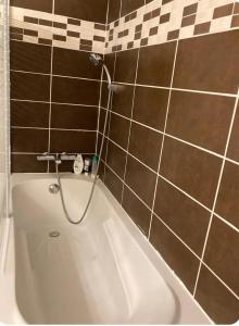 a bath tub in a bathroom with brown tiles at City centre appartement en colocation in Chambéry