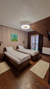 two beds in a large room with wooden floors at Pensiunea Terra Nova in Brezoi