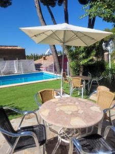 a table and chairs with an umbrella next to a pool at Villa Pachita (por habitaciones) in Alhama de Aragón