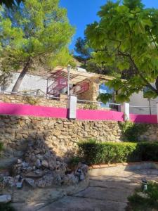 a stone wall with a building with a pink wall at Villa Pachita (por habitaciones) in Alhama de Aragón