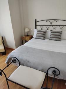 a bedroom with a large white bed and a chair at Luz de la Avenida in Tomelloso