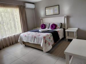 a bedroom with a bed with purple pillows and a window at OppiDam Gastehuis in Vanderkloof +15 photos