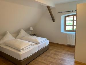 a bedroom with a bed with white sheets and a window at Stanglbräu in Hausen
