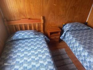 two beds in a small room with wooden walls at Cabaña Terraza del Yates in Puerto del Yate