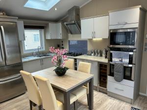 a kitchen with a table with a vase of flowers on it at Tulip 10, Oakdene Forest Park , passes included in Saint Leonards