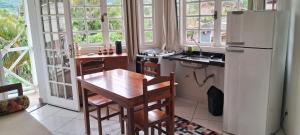 a kitchen with a wooden table and a refrigerator at Kasa Mare studios Maresias in São Sebastião