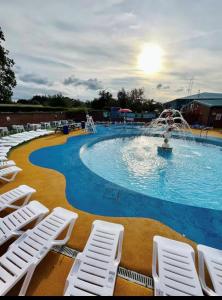 a swimming pool with white chairs and a fountain at Tulip 10, Oakdene Forest Park , passes included in Saint Leonards