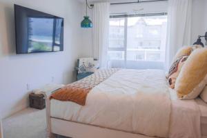 a bedroom with a bed with a television and a window at Lakefront Haven Mtn View Condo Steps from Beach in Harrison Hot Springs