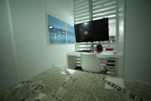a bed with a newspaper on it with a television at Flat Farol da Barra 2 in Salvador