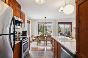 a kitchen with wooden cabinets and a dining room at Cozy Golfside Oasis Fireplace and Terrace in Mont-Tremblant