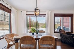 a dining room with a table and chairs and windows at Cozy Golfside Oasis Fireplace and Terrace in Mont-Tremblant +10 photos