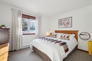 a white bedroom with a bed and a window at Cozy Golfside Oasis Fireplace and Terrace in Mont-Tremblant