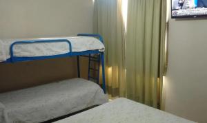 a small room with two bunk beds and a television at Hotel Necochea in Mendoza +5 photos