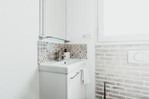 a white bathroom with a sink and a brick wall at Studio - Normandy 1 in Le Havre